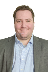 A man wearing a blue shirt and a gray jacket. Description generated by AI