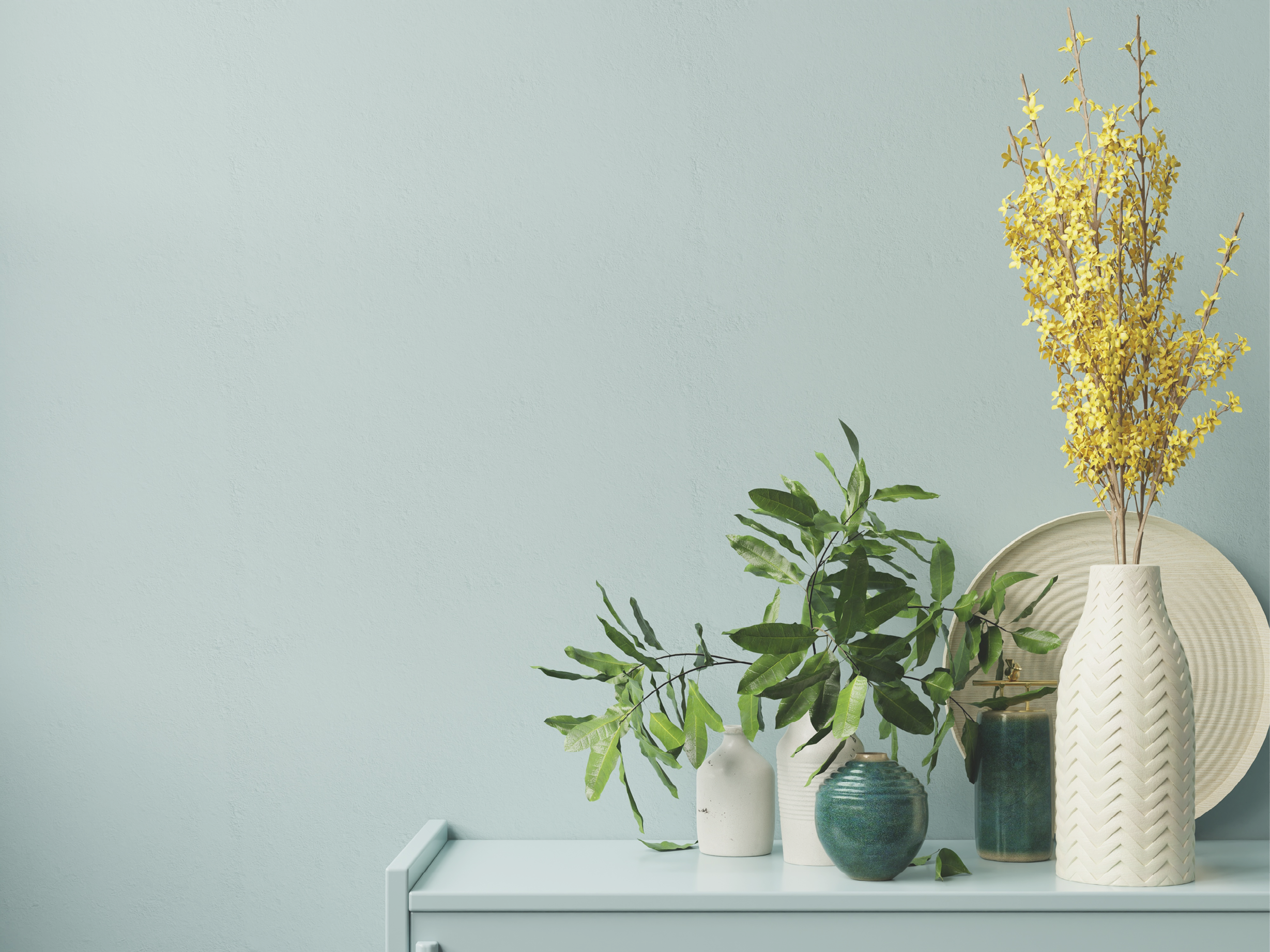 A vase with yellow flowers and a plant with green leaves. Description generated by AI
