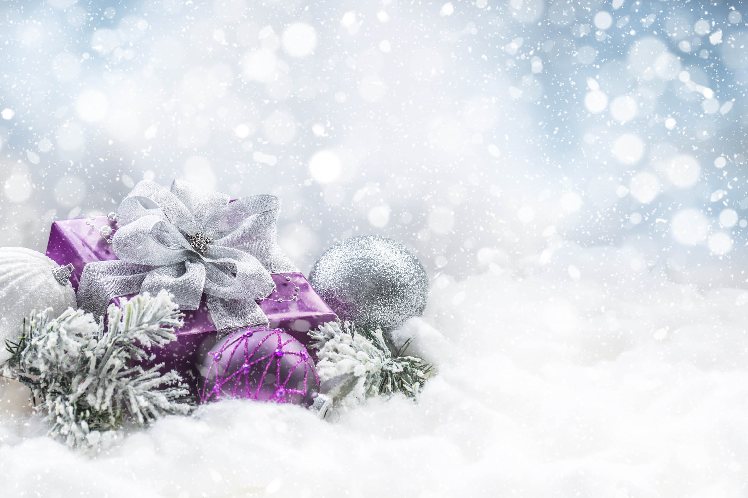 Purple christmas gift and balls on snow with fir branches. Merry Xmas concept.