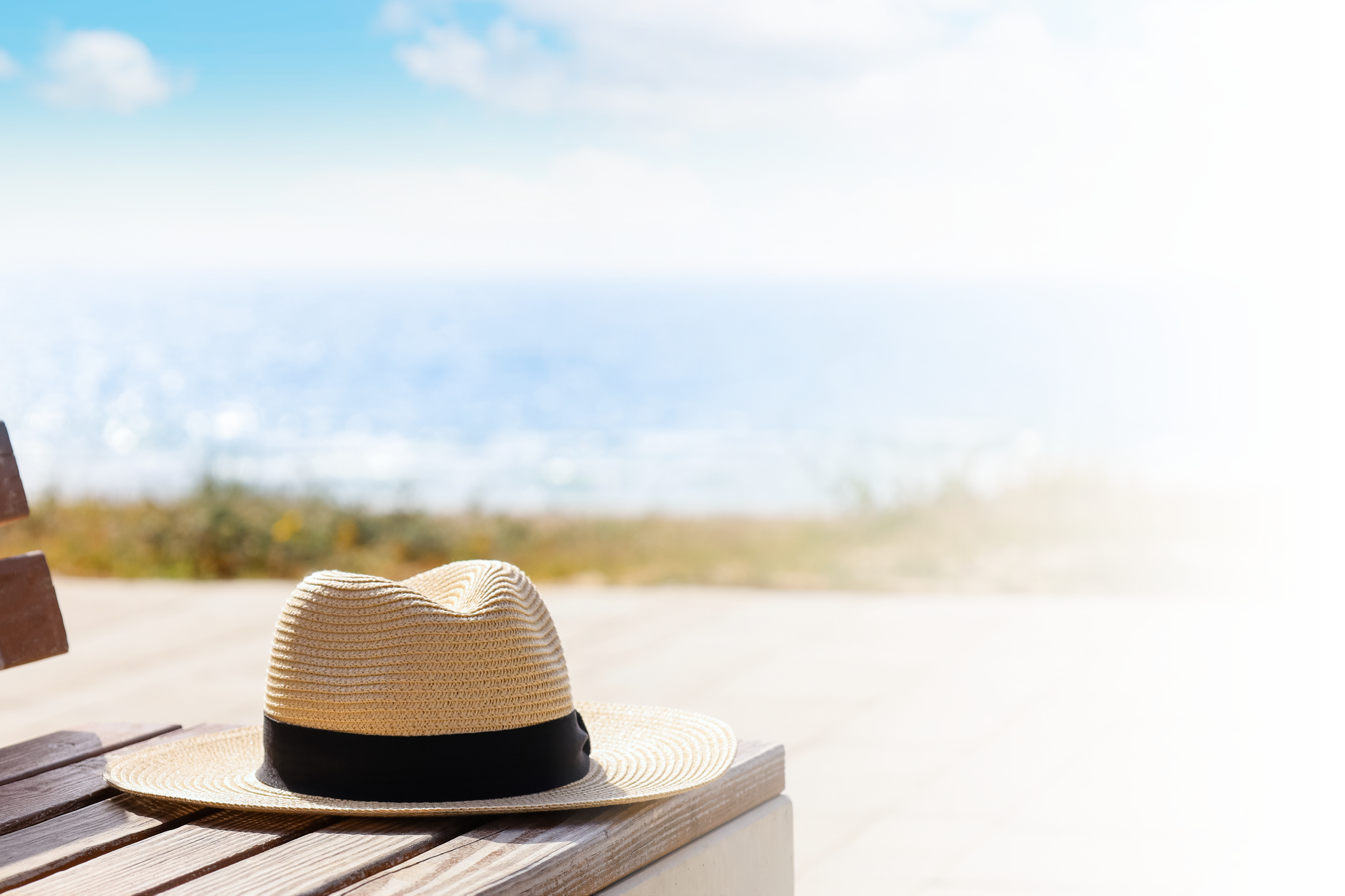 A tan hat is on a wooden bench. Description generated by AI